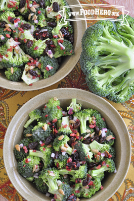 A bowl is filled with crunchy salad featuring broccoli, raisins and sunflower seeds.