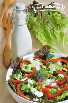 Bottle of creamy dressing shown served over a salad. 
