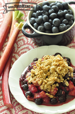 Bowl of baked rhubarb and blueberries with a crumbly oat topping. 