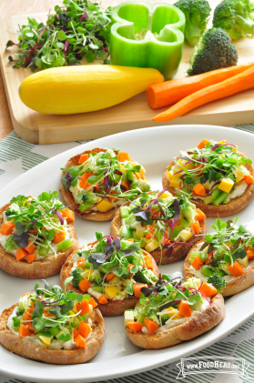Platter of eight English muffins layered with a creamy sauce and vegetable topping.