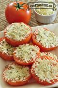 Sliced tomatoes with herbs and broiled cheese are shown on a serving platter. 