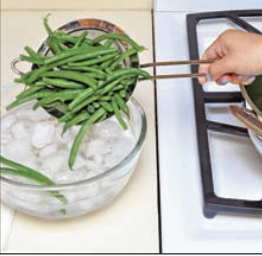 Green beans being dipped in ice cold water.
