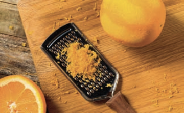 Grater with orange zest on top of it