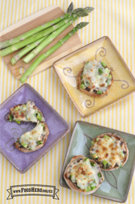 Panecillos ingleses cubiertos con espárragos picado, hongos y queso asado se muestran en platos.