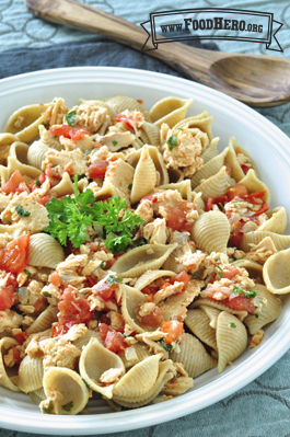 Bowl of pasta shells and salmon garnished with parsley.