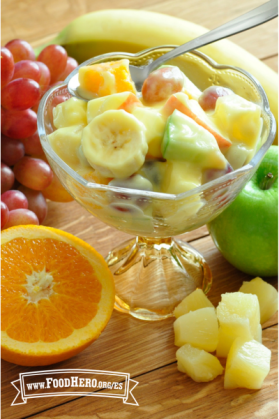 Plato de cristal con pie con una ensalada cremosa de frutas.