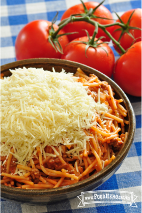 Tazón grande de espaguetis cubiertos con queso parmesano rallado.