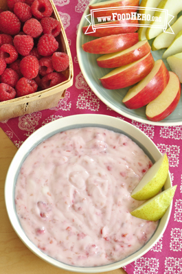 Bowl of yogurt raspberry dip served with sliced apple and pear.