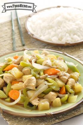 Plate of diced pineapple, vegetables and chicken served with rice.