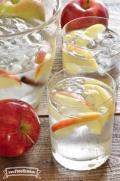 Glasses of refreshing Apple Cinnamon Flavored Water are shown with an apple slice garnish.