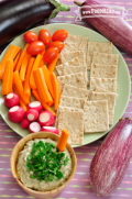 Eggplant dip garnished with parsley served with a vegetable and cracker plate.