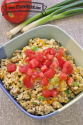 Bowl of cheesy oatmeal topped with chopped tomatoes.