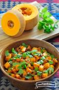 Wooden bowl of seasoned butternut squash, pumpkin seeds and fresh herbs.