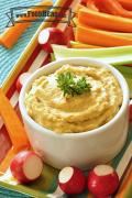 Hummus garnished with parsley served with carrot sticks, celery and radishes.