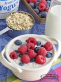 Ceramic bowl with creamy oatmeal topped with raspberries and blueberries.