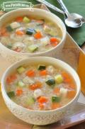 Two bowls of soup filled with rice, chicken and vegetables.