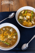 Bowl of soup with asparagus and potatoes topped with cheddar cheese.