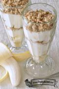 Glass cups with layers of yogurt, banana and granola.