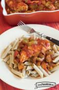 Tender chicken cooked in a tomato and spice-based sauce served over a bowl of pasta.