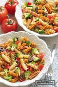 Bowls of colorful spiral pasta with olives and broccoli.