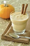 Glass of thick smoothie served with cinnamon sticks.