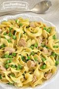 Bowl of egg noodles with peas and tuna mixed in.