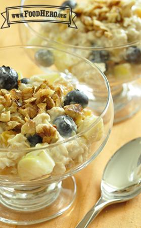 Bowl of oatmeal and yogurt topped with fruit and walnuts. 