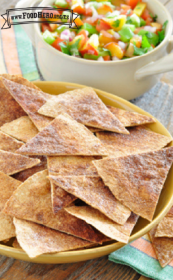 Chips de tortilla espolvoreados con canela se muestran en un plato con un tazón de salsa de durazno.