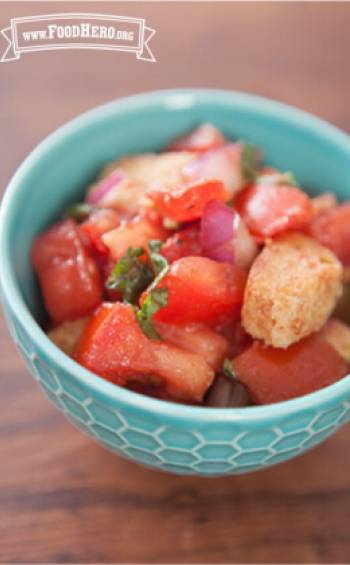 Flavorful salad of tomatoes, basil and croutons is shown in a serving bowl.