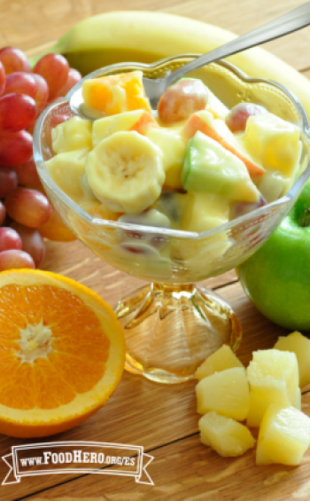Plato de cristal con pie con una ensalada cremosa de frutas.