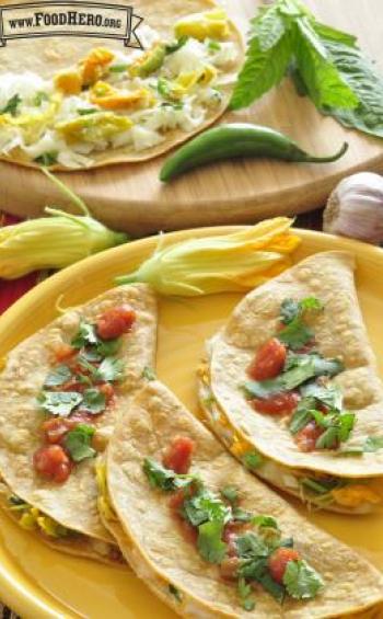 Plate of corn tortillas folded over cheese and squash blossom filling with salsa.