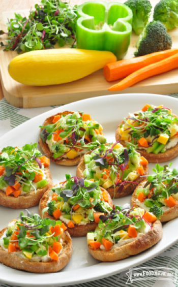 Platter of eight English muffins layered with a creamy sauce and vegetable topping.