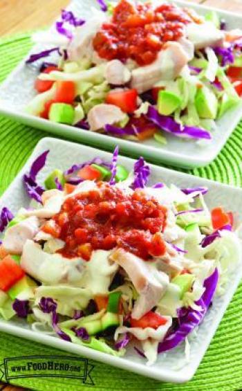 Plates with cabbage and vegetables below a fish, ranch and salsa topping.