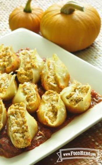 Plate of pasta shells filled with pumpkin and cheese filling over red pasta sauce.